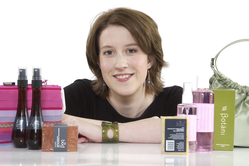 A smiling woman pictured with beauty products.