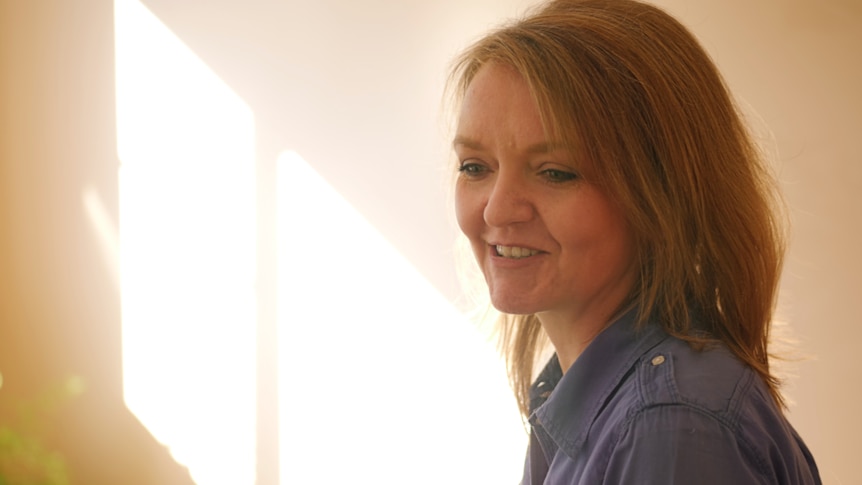 Woman smiles at something, light in the background