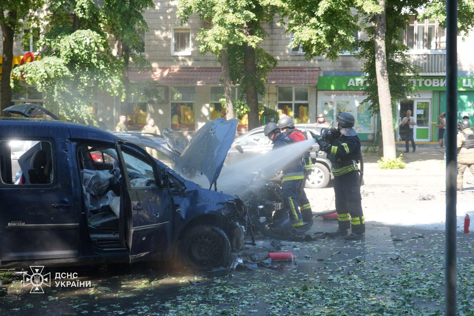 Firefighters spray a burnt out car with hoses. 