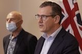 NT Chief Minister Michael Gunner and Chief Health Officer Hugh Heggie stand at a lectern looking concerned.