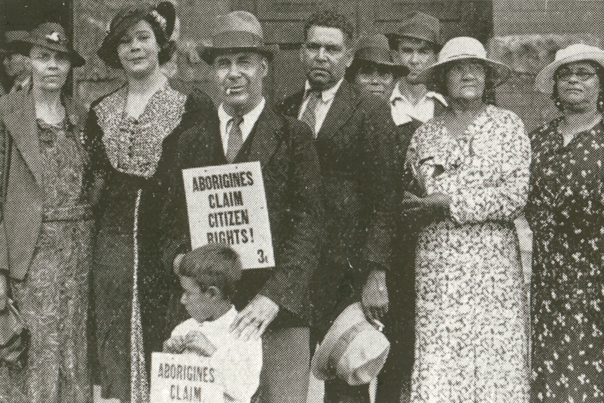 A black and white photo of Aboriginal men and women in 1938, holding a sign that reads "Aborigines claim citizen rights!"