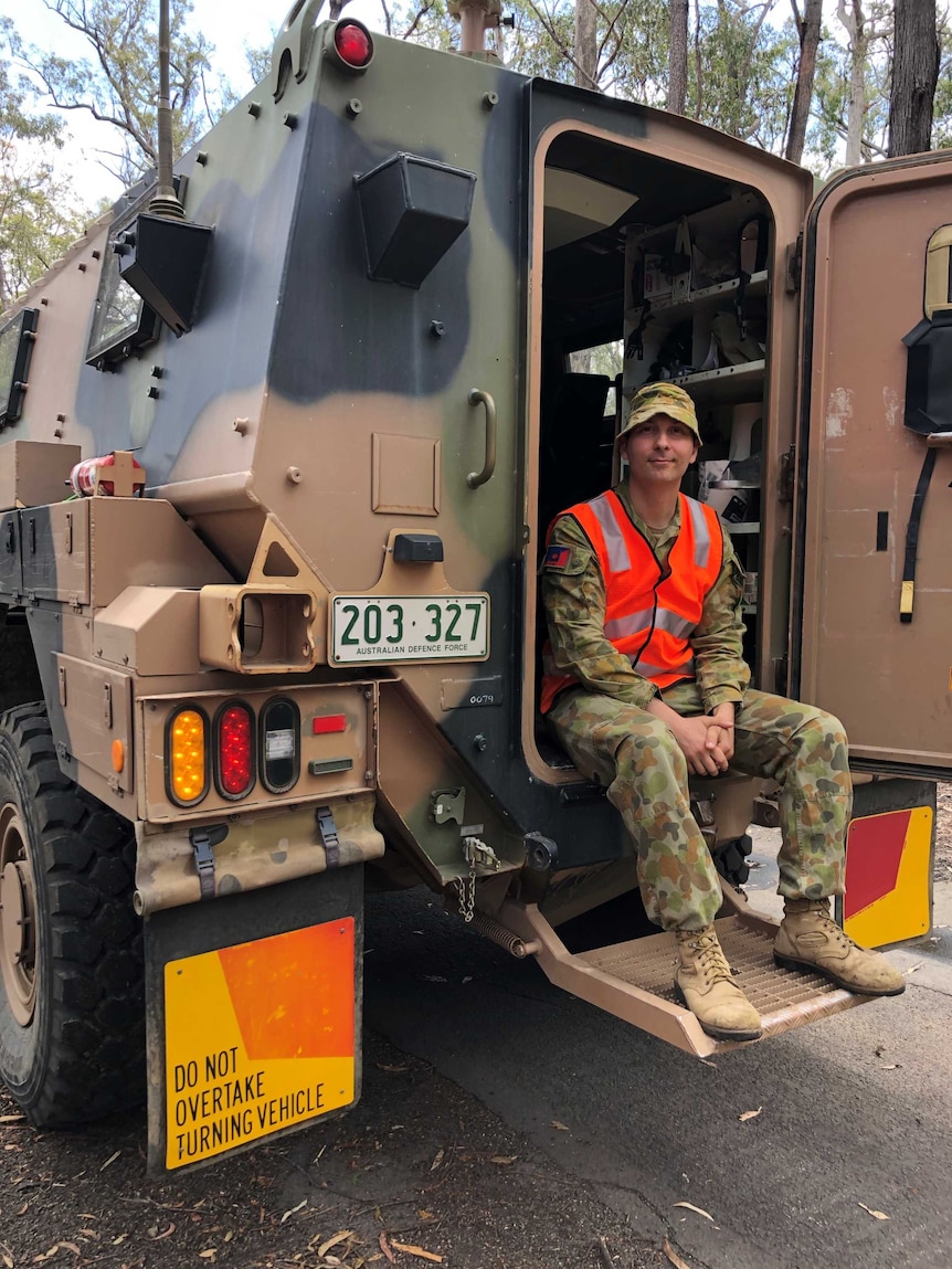 A man in army clothing sitting in the back of an Australian Defence Force truck.
