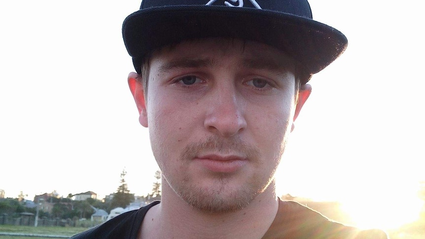 A Selfie-style shot of a young man wearing a flat-brimmed cap standing outside with the sun shining over his shoulder.