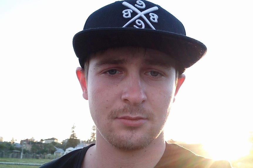 A Selfie-style shot of a young man wearing a flat-brimmed cap standing outside with the sun shining over his shoulder.