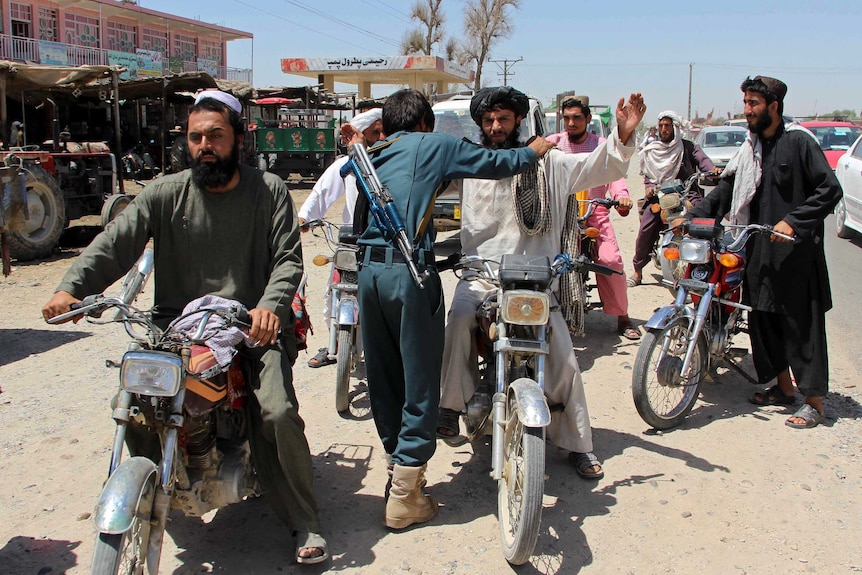 An Afghan policeman searching commuters at a checkpoint in Helmand province.