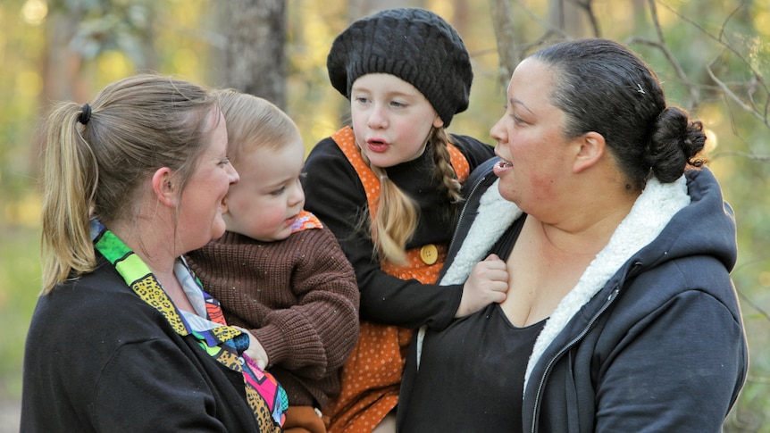 Two woman holding their two children.