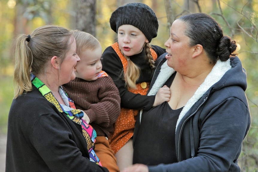 Two woman holding their two children.