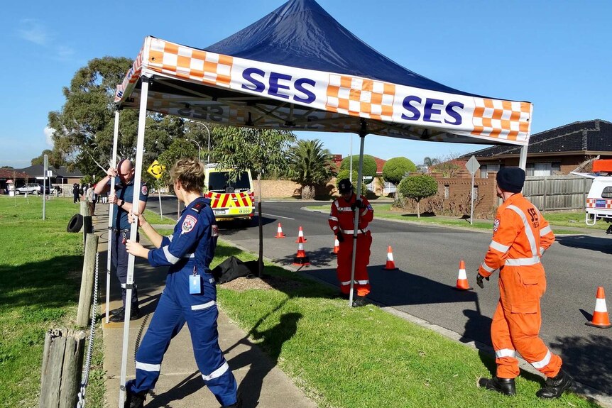 SES volunteers set up a gazebo in a street on a sunny day