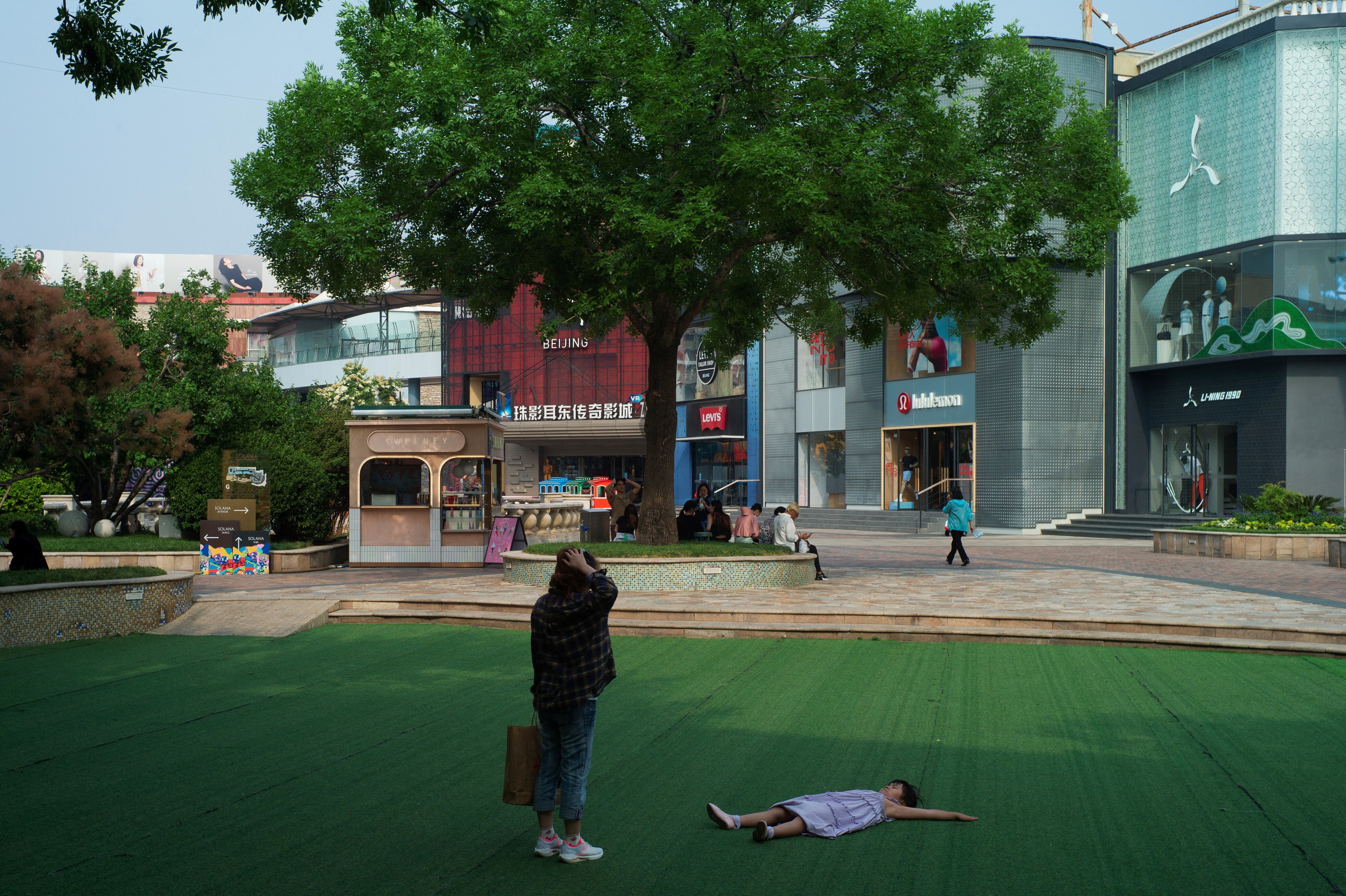 A few people walking in front of a shopping mall in China. 