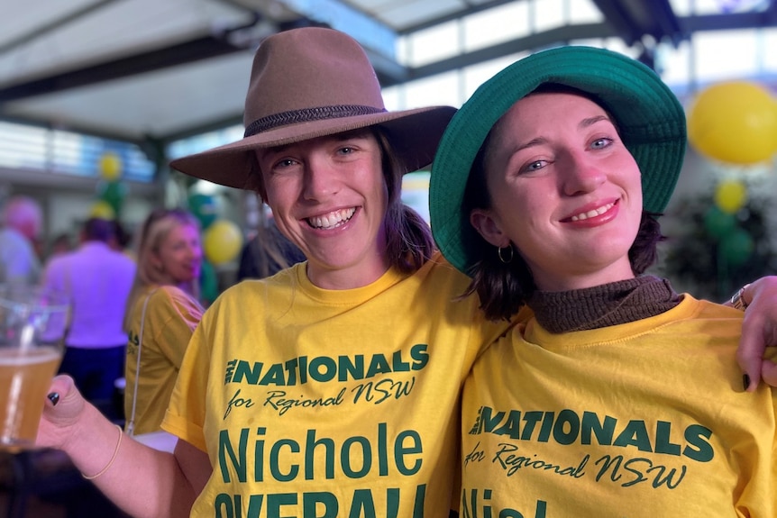 Two women with drinks smile at the camera.