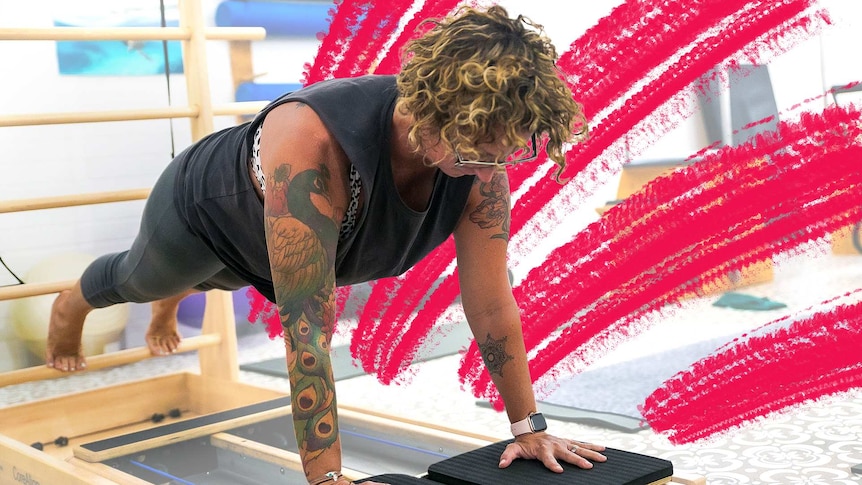 A woman in a push up stance uses a Pilates machine.