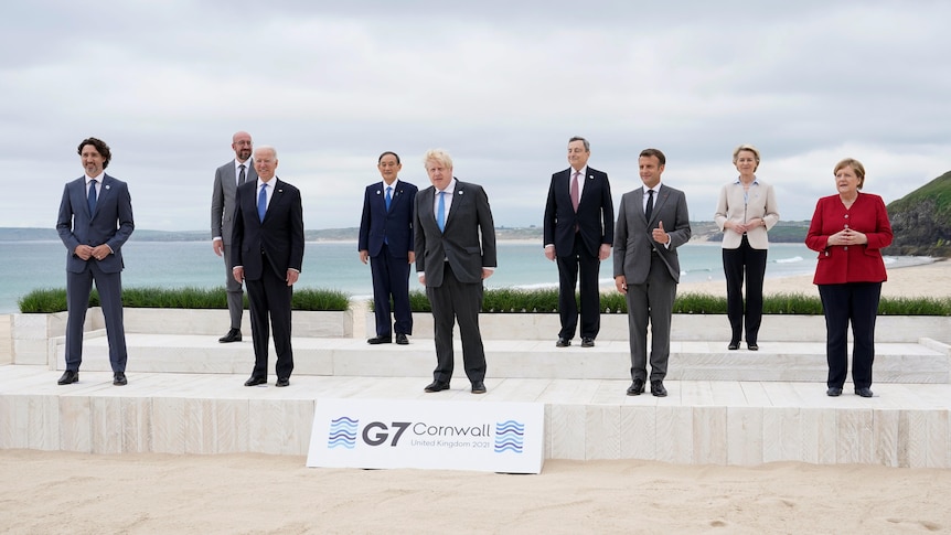 The leaders of the G7 pose for a group photo near the sea.