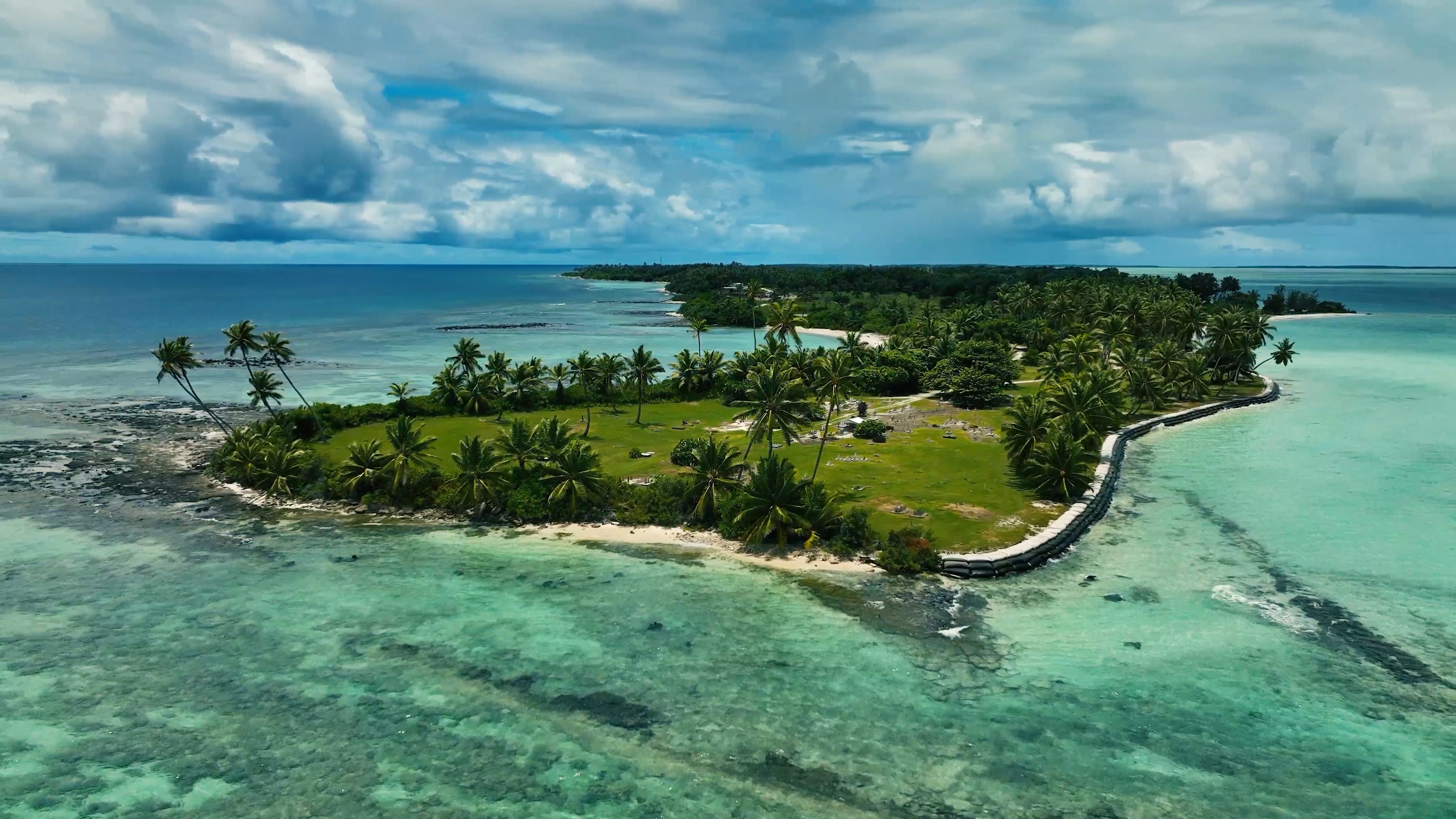 An island with palm trees surrounded by turquoise water.