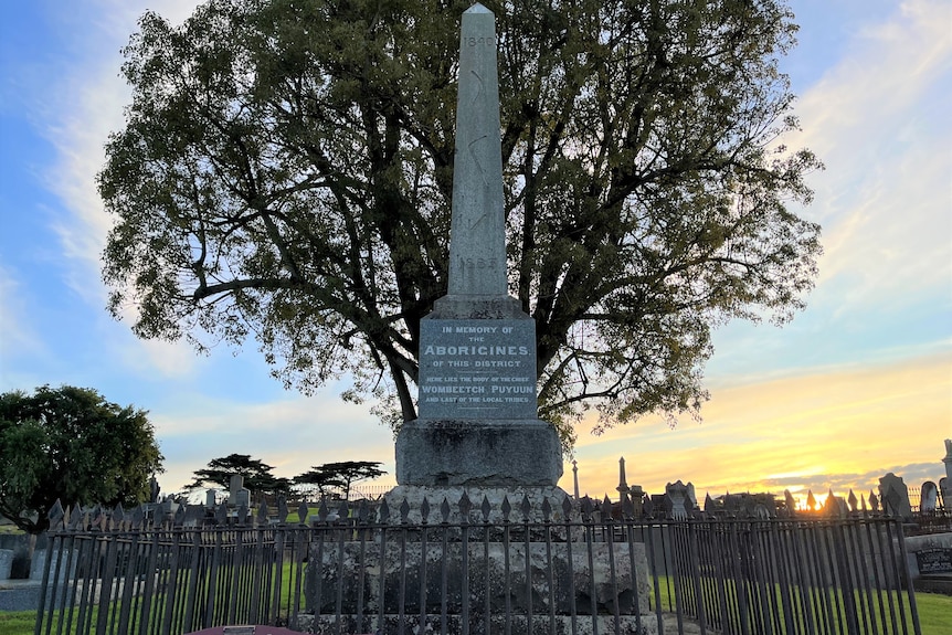 A tall obelisk in a cemetery at dusk