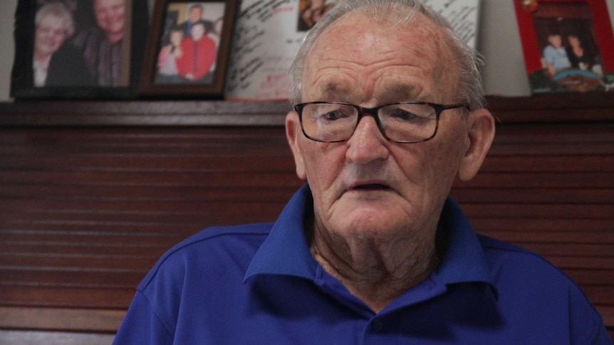 A headshot of an older man wearing glasses and a blue shirt.