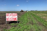 Tractor in field with a sign protesting a 16km inland rail line proposed to be built on floodplain at Millmerran.