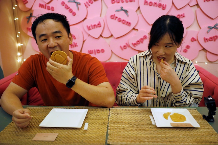 Two people lick honeycomb pieces replicating a game from the series Squid Game