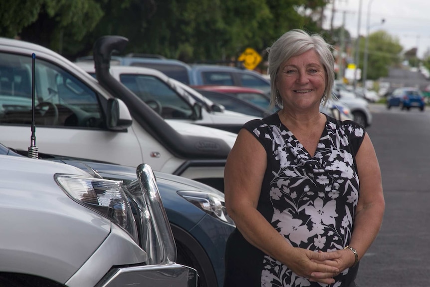 A woman standing in front of parked cars