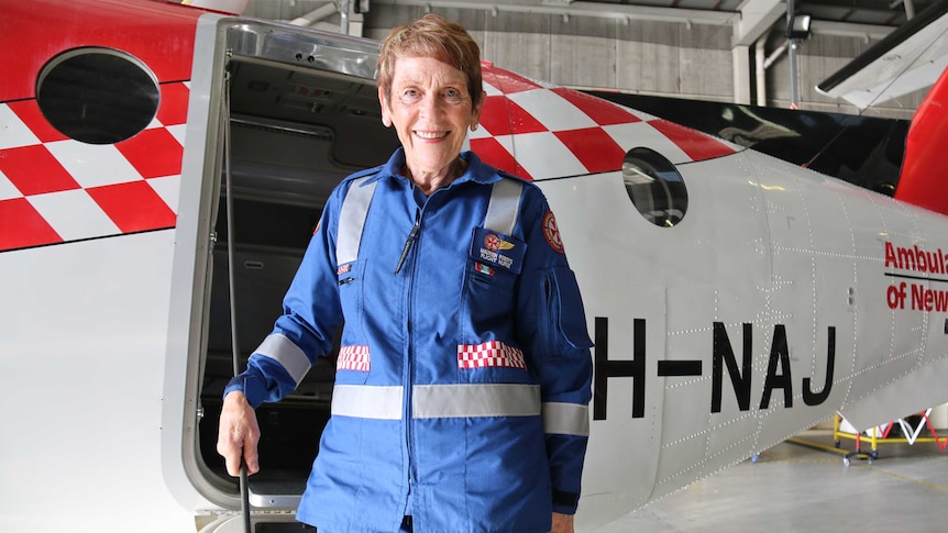 A woman stands on the steps of an aircraft