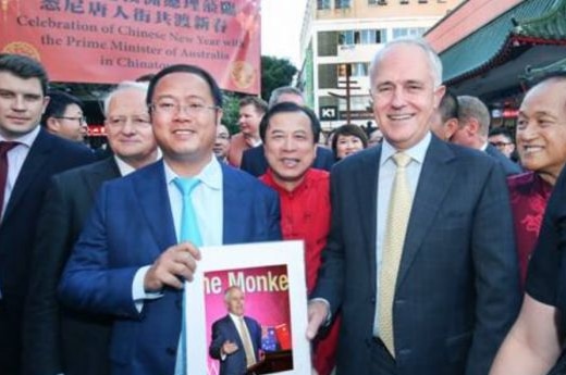 Huang Xiangmo stands with Malcolm Turnbull in front of a crowd holding a picture of Turnbull.