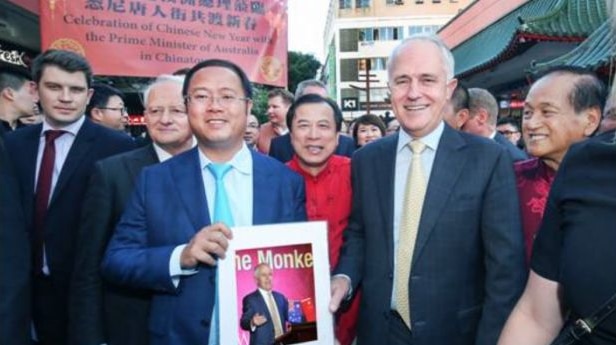 Huang Xiangmo stands with  Malcolm Turnbull in front of a crowd holding a picture of Turnbull.