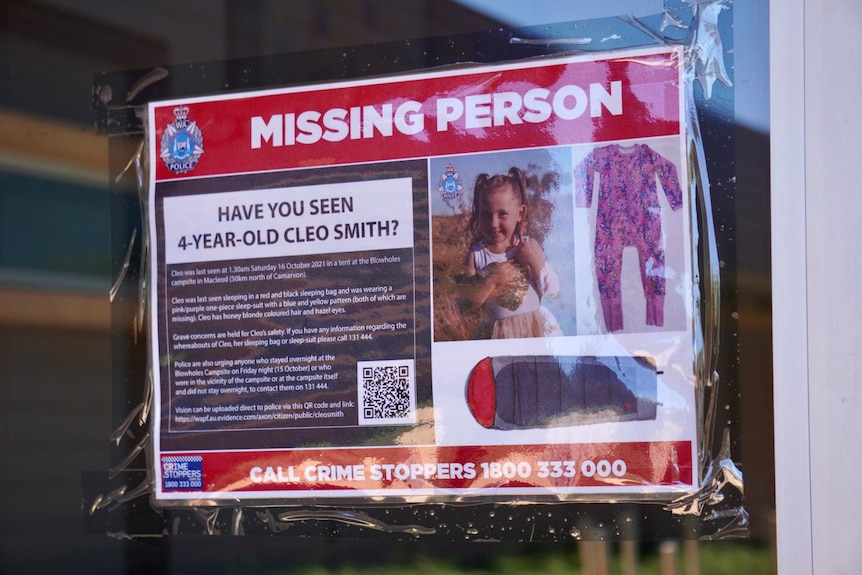 A close-up shot of a Cleo Smith missing person poster displayed in a window.