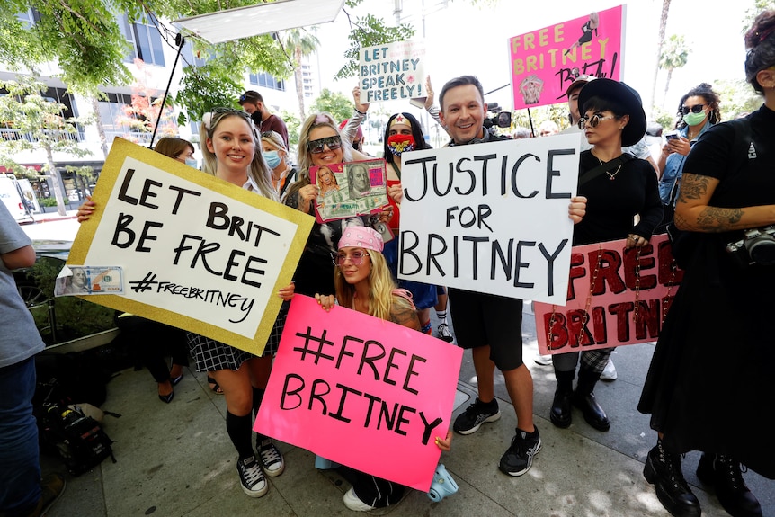 A group of people stand outside a court holding Free Britney signs