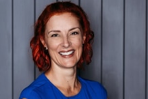 Headshot of smiling woman with blue blouse and red hair.