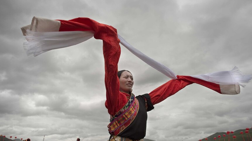 An ethnic Tibetan woman wearing a traditional costume dances at a festival