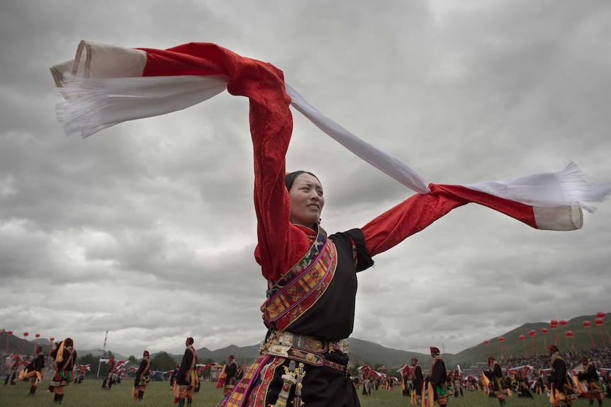 An ethnic Tibetan woman wearing a traditional costume dances at a festival