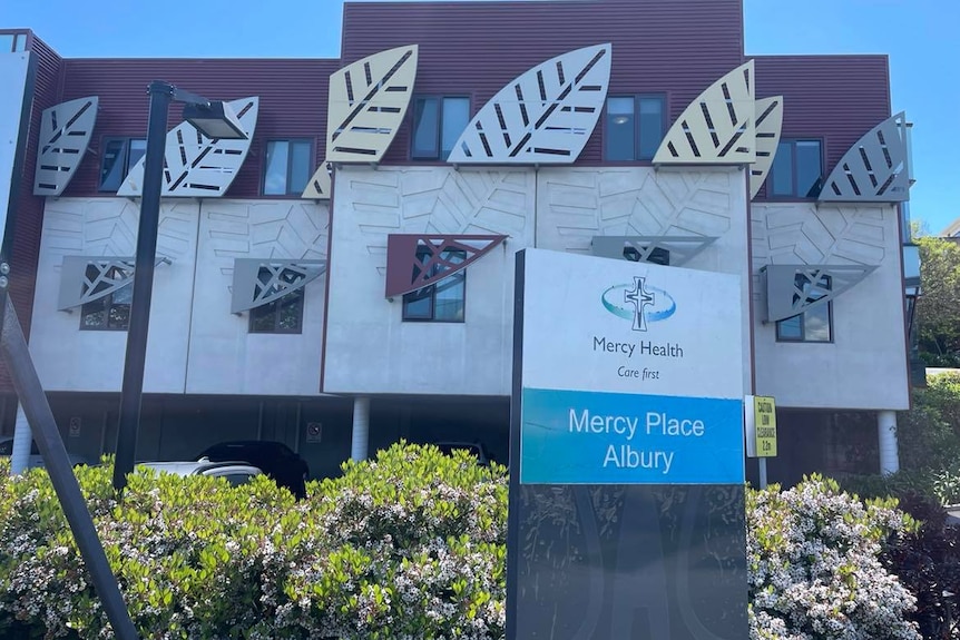 A sign that reads "Mercy Place" in front of a bright building.