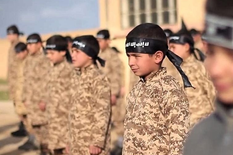 Children stand in a line wearing military uniforms and Islamic State head bands.