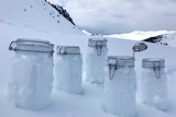 Snow samples sit in five jars in Switzerland on the snow.