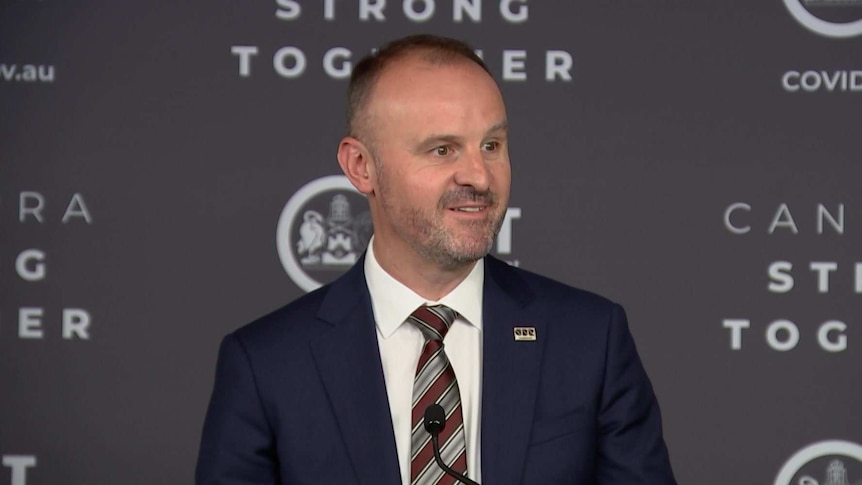 A man in a suit speaks at a podium.