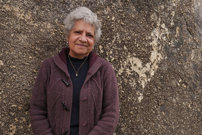 a woman standing in front of a rock