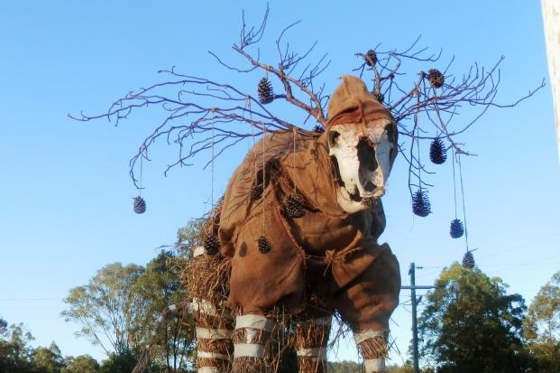 A scarecrow shaped like a deer, made of star pickets, straw, hessian bags and cow skull with branches and pine cones as antlers