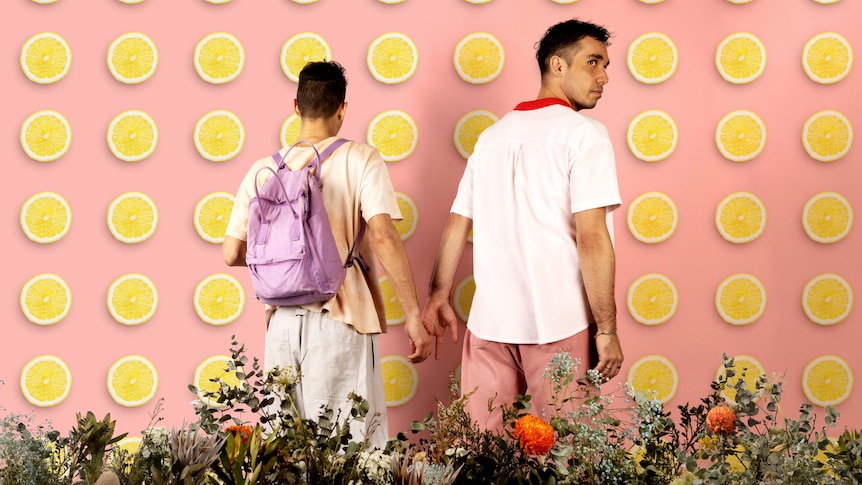 Ty and Neddy stand hand in hand in front of Lemon themed wallpaper