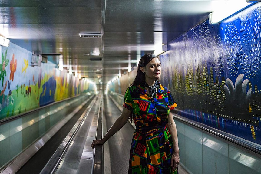 Midshot colour photograph of artist and writer Vanessa Berry standing in the Domain Express Walkway
