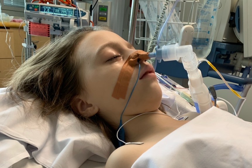 Hayley Minson-Rivers laying in a hospital bed with a tube attached to her nose