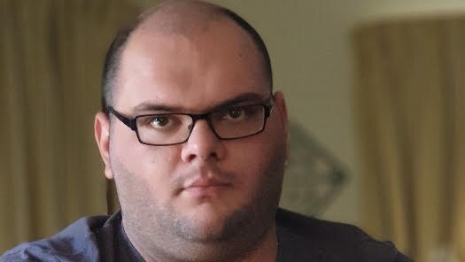 A man sits at a desk with a laptop.