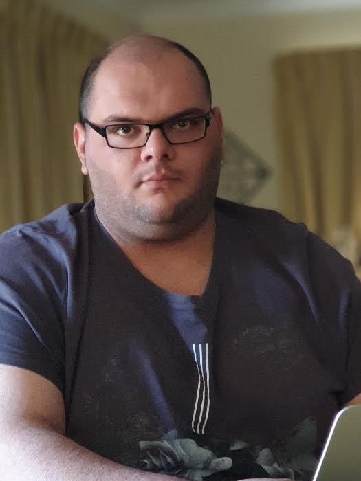 A man sits at a desk with a laptop.