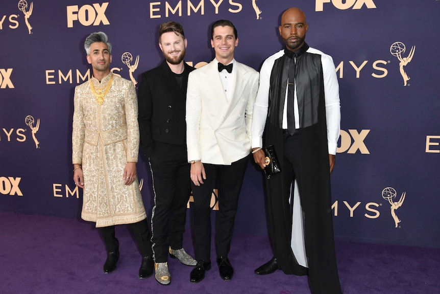 Tan France, Bobby Berk, Antoni Porowski and Karamo Brown stand next to each other against a purple backdrop on the purple carpet