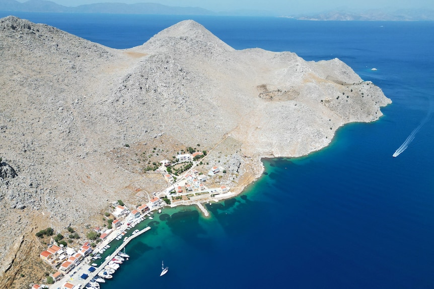 A wide shot of Symi island featuring rocky mountains surrounded by deep blue water