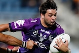 A Wests Tigers NRL player turns to is left as he attempts to tackle a Melbourne Storm opponent.