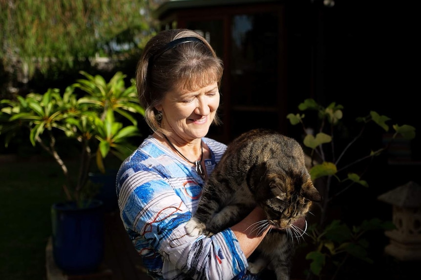 A woman holding her cat looking down at it.