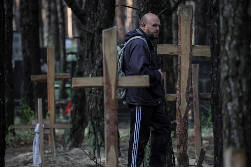 A man walking among graves in the Ukrainian town of Izium.