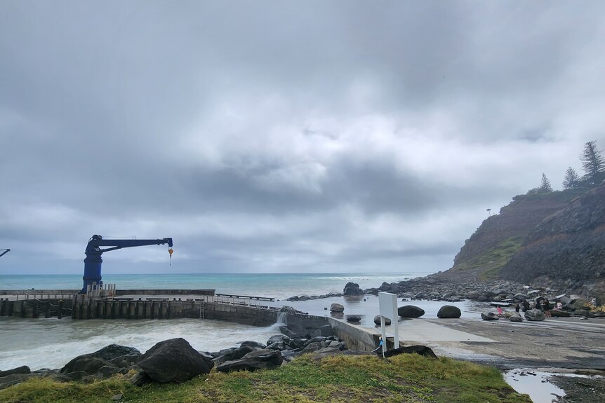 large rocks thrown up onto the pier and a grey outlook at norfolk island
