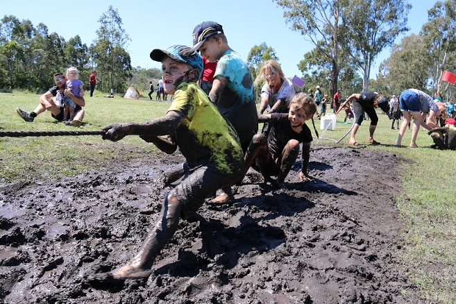 Muddy kids playing tug-of-war.