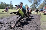 Muddy kids playing tug-of-war.