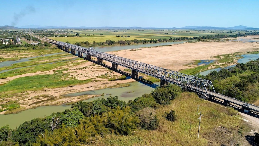 Aerial shot of a rail bridge over a river with wide sand banks.